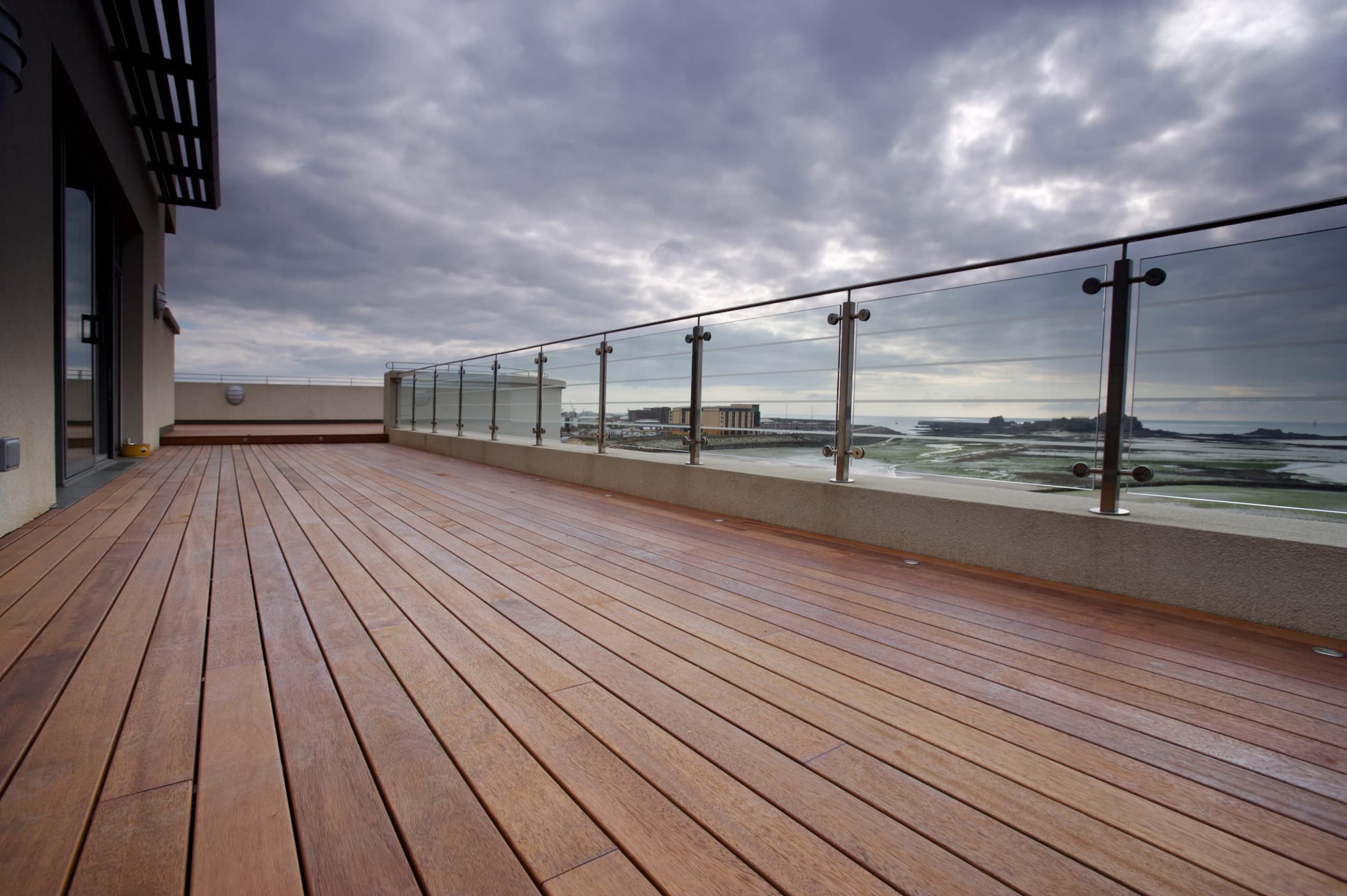Balcony in jersey made of wood decking merbau premium softline exotic wood next to the sea with a beautiful view by Vetedy