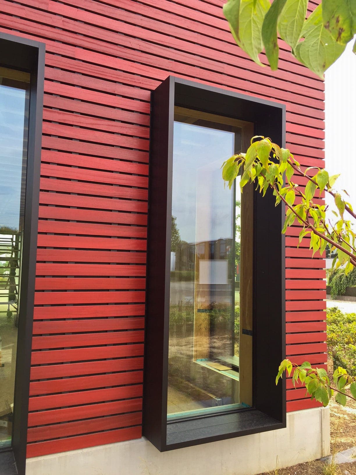 Factory building with stained red padauk with the invisible system techniclic by Vetedy in Belgium for the company Omniwood