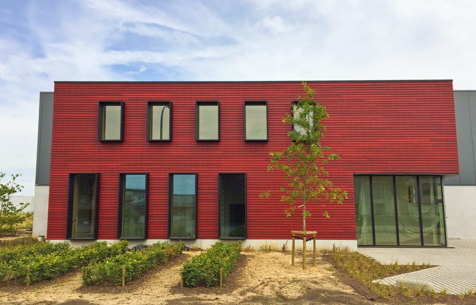 Factory building with stained red padauk with the invisible system techniclic by Vetedy in Belgium for the company Omniwood