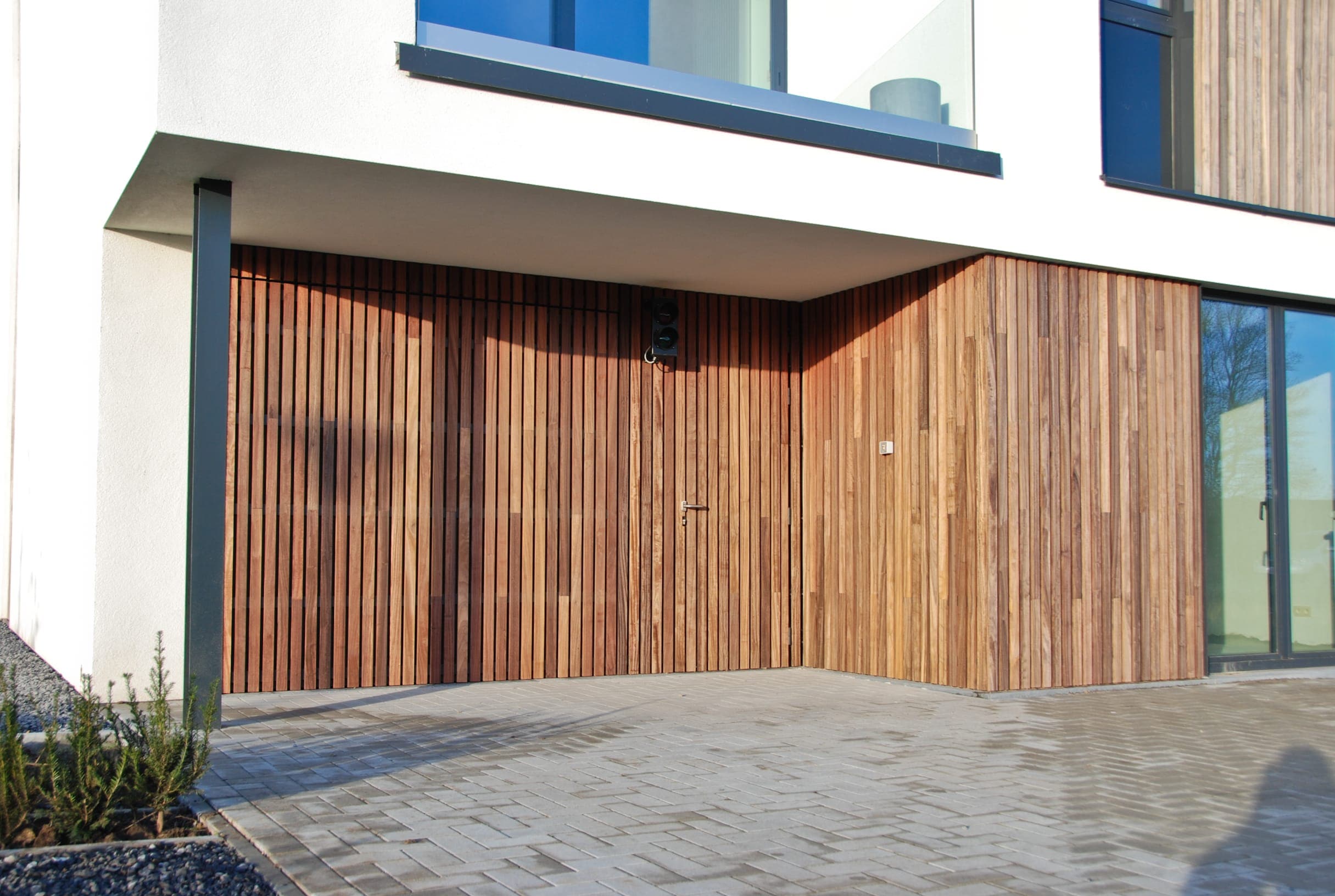 Bardage en bois padouk Incredible wood cladding with padauk on building in belgium with a garage door in wood cladding without visible fixations vetedy techniclic